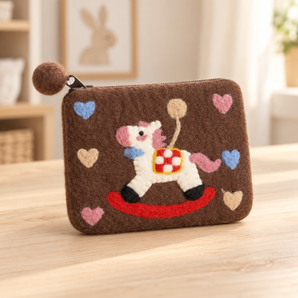 Brown felt rocking horse coin purse styled on a pale wooden table